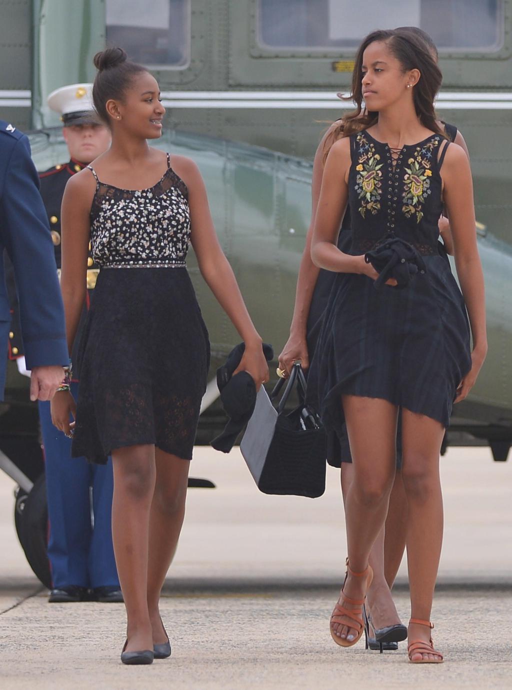 Sasha (L) und Malia (R), die Töchter von US-Präsident Barack Obama und First Lady Michelle Obama, machen sich auf den Weg zur Air Force One, bevor sie am 30.August 2014 von der Andrews Air Force Base in Maryland abfliegen. Obama kehrt nach Westchester County, New York, zurück, um an der Hochzeit seines persönlichen Küchenchefs Sam Kass teilzunehmen. AFP FOTO / Mandel NGAN (Bildnachweis sollte MANDEL NGAN / AFP / Getty Images lesen)